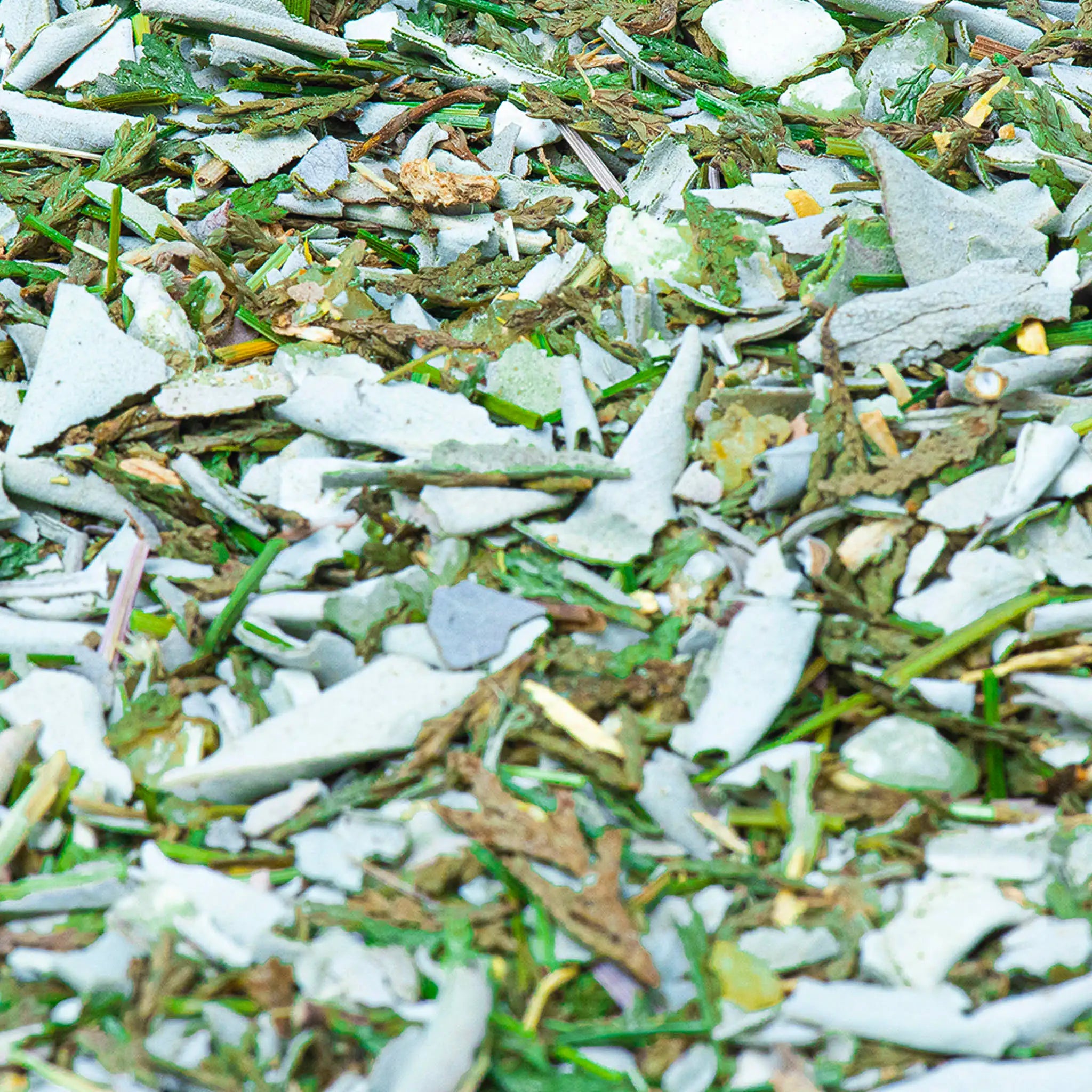 Detaliu de amestec botanic ASHIRA pentru fumigatie, cu plante uscate, seminte si accente verzi naturale.