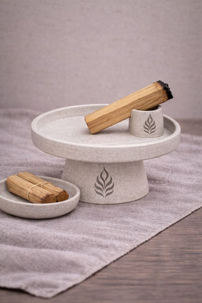 Suport ceramic ritualic cu chibrit palo santo sprijinit in unghi, tava pentru colectarea cenusii si elemente de context pe fundal textil neutru