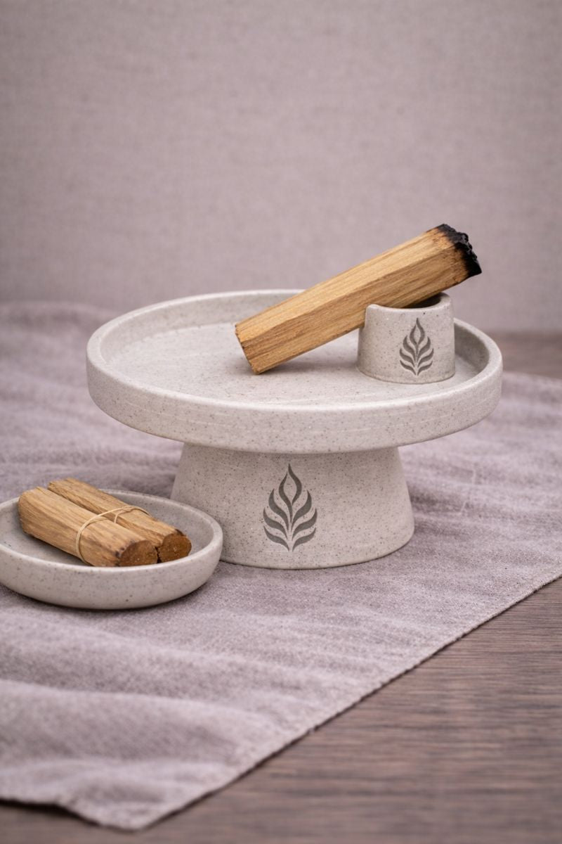 Suport ceramic ritualic cu chibrit palo santo sprijinit in unghi, tava pentru colectarea cenusii si elemente de context pe fundal textil neutru